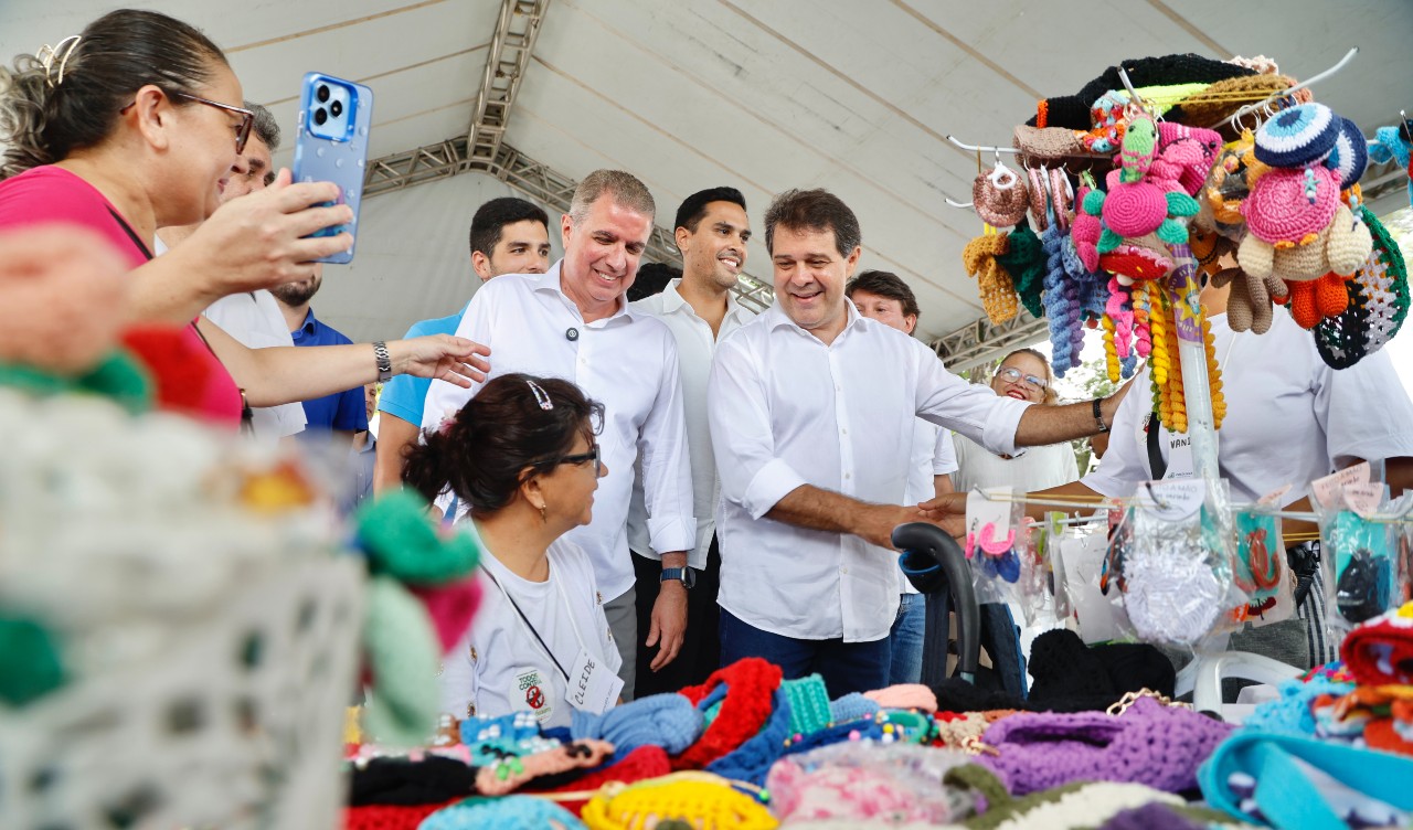 prefeito cumprimenta uma mulher num estande montado na feira